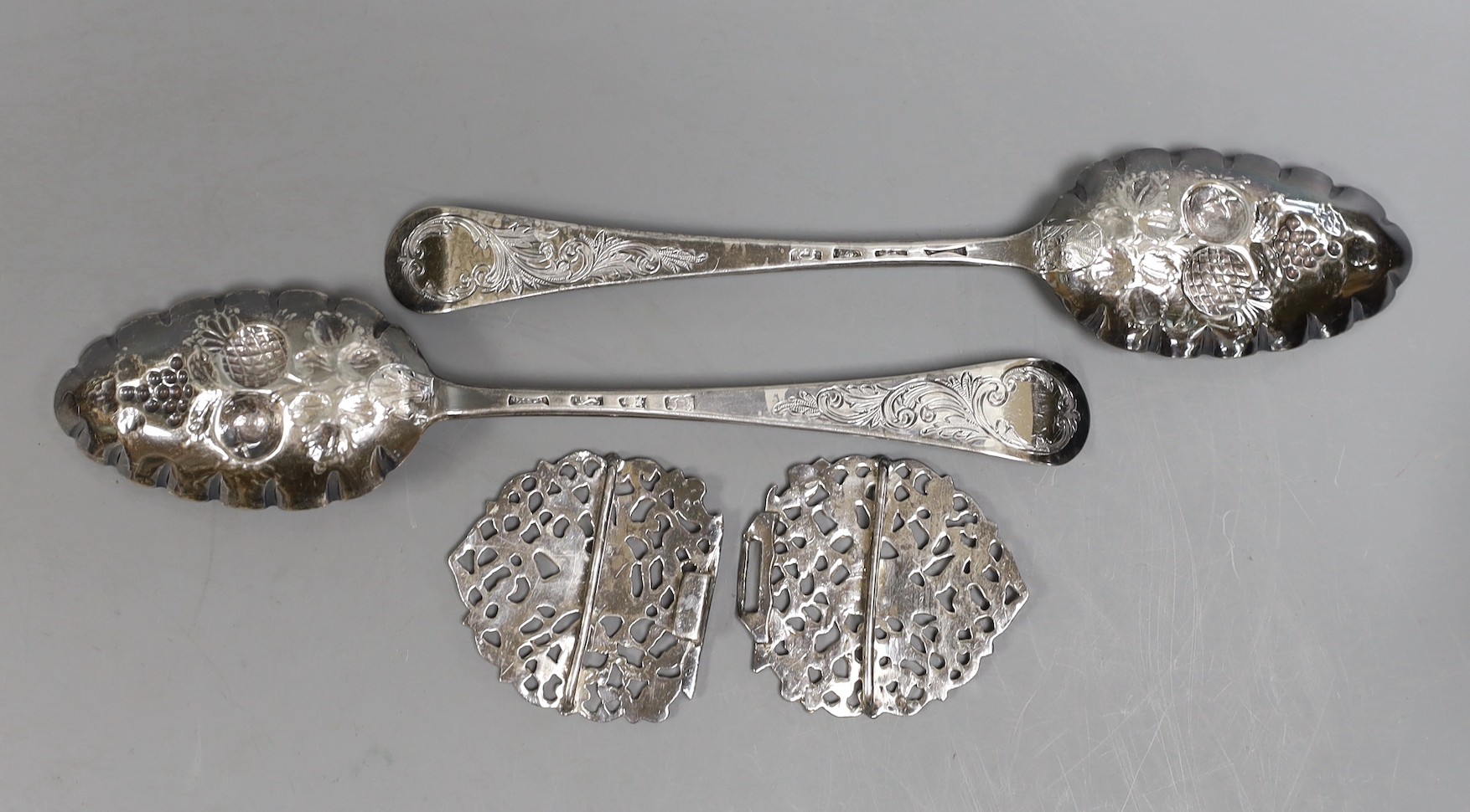 A pair of George III silver Hanovarian pattern 'berry' spoons, Jacob Marsh?, London, 1768, 20.5cm, together with an Edwardian pierced silver nurses buckle, Chester, 1907, decorated with herons, width 10.5cm.